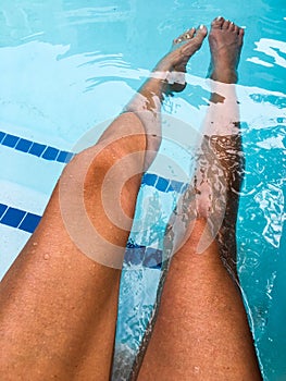 Young womanÃ¢â¬â¢s long tan legs in bright blue pool water photo